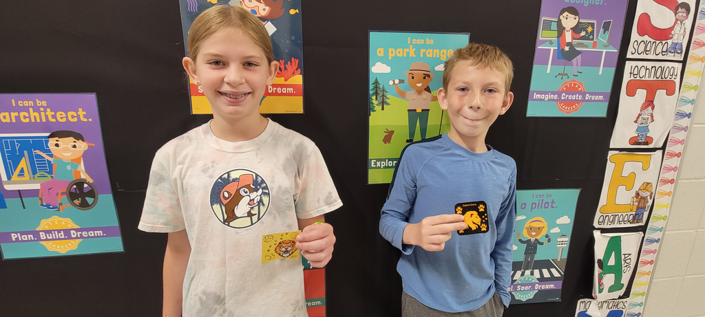 Two students holding stickers they created in class. 